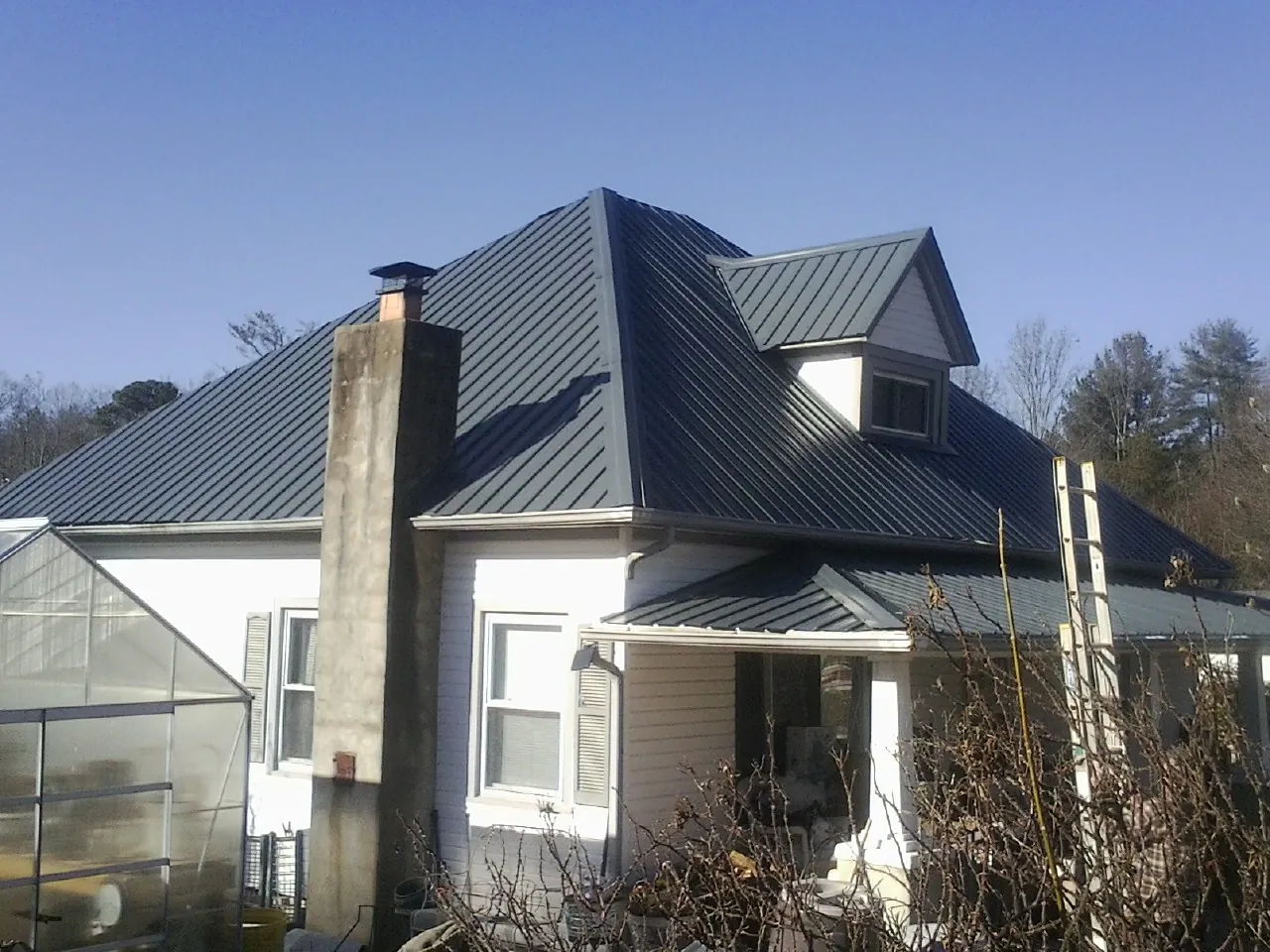 Dark blue standing seam metal roof on a white farmhouse with dormer — Slate & Tile Roof Repair by Roofing Brothers in Silver Lake